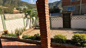 A courtyard with a brick pillar, a paved area, and a white wall with a gate. - cabaña a 10 minutos de la playa, taganga , colombia (Santa Marta)