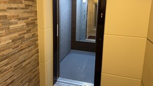 Ein Aufzug mit einer Spiegelwand, einem gefliesten Boden und einer Tür, die die Etage anzeigt.