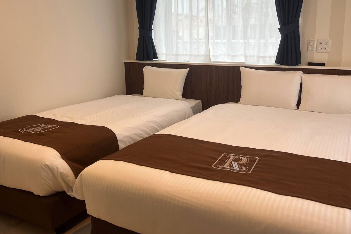 A hotel room with two single beds, each with a brown headboard and a white pillow.