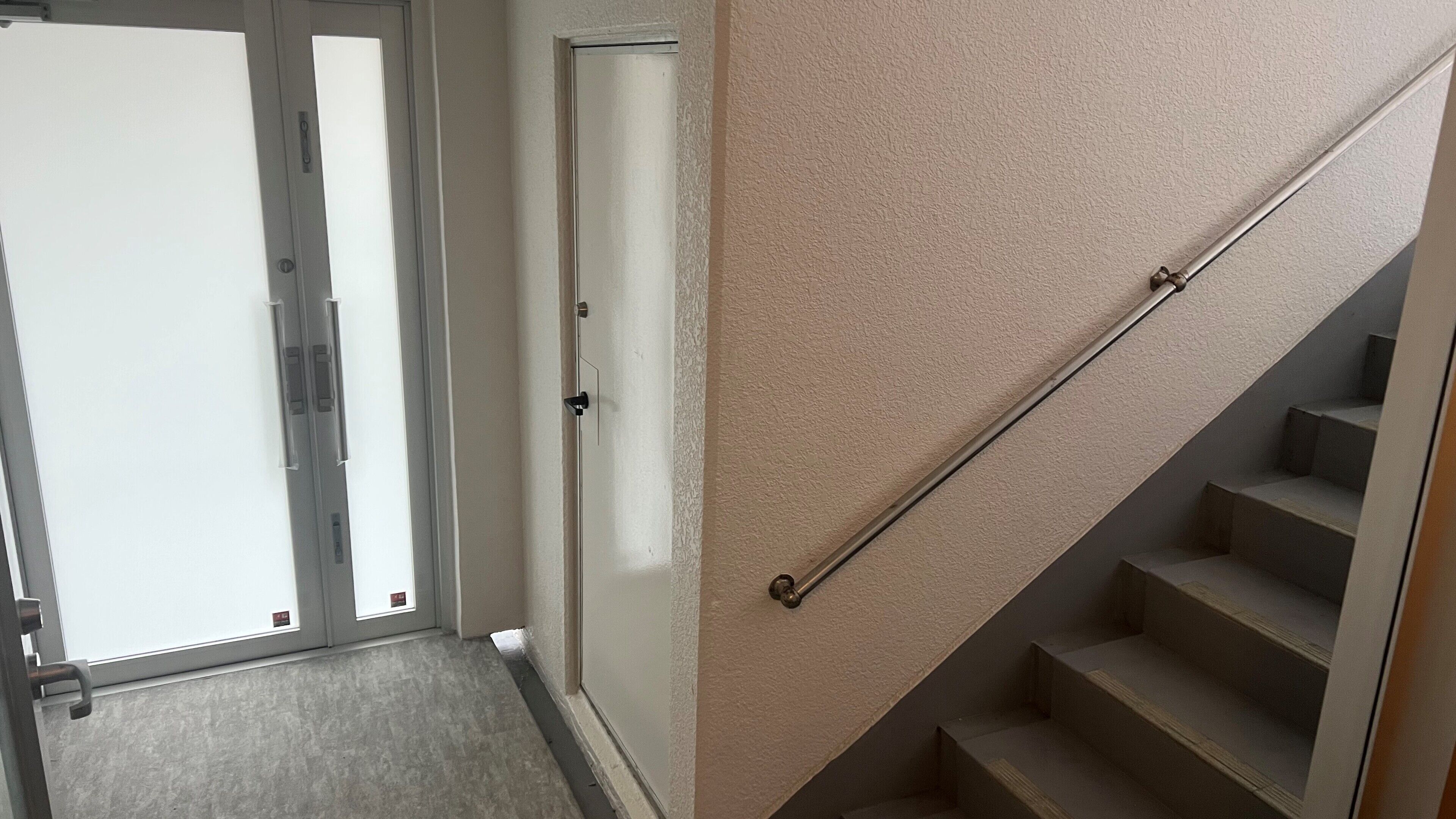 Un pasillo con una puerta, una escalera y un revestimiento de pared con textura.