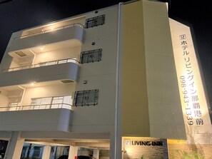 Un hôtel à plusieurs étages, doté de balcons et d’une enseigne bien visible indiquant le nom de l’établissement et son numéro de téléphone.