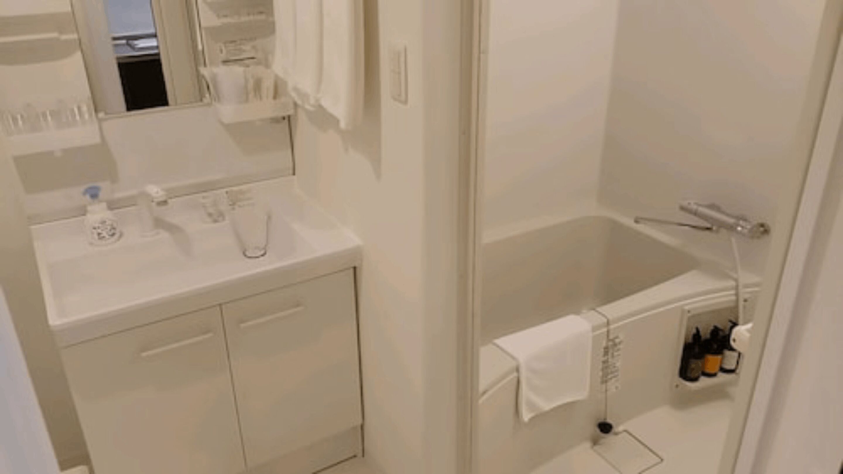 A bathroom with a white sink, mirror, and a shower area with a towel rack.
