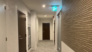 Ein Flur mit strukturierter Wand, einer Holztür und einer Ziegelwand.