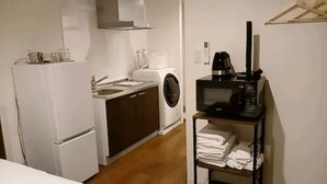 Eine kompakte Küche mit Kühlschrank, Waschmaschine, Mikrowelle und Kaffeemaschine.