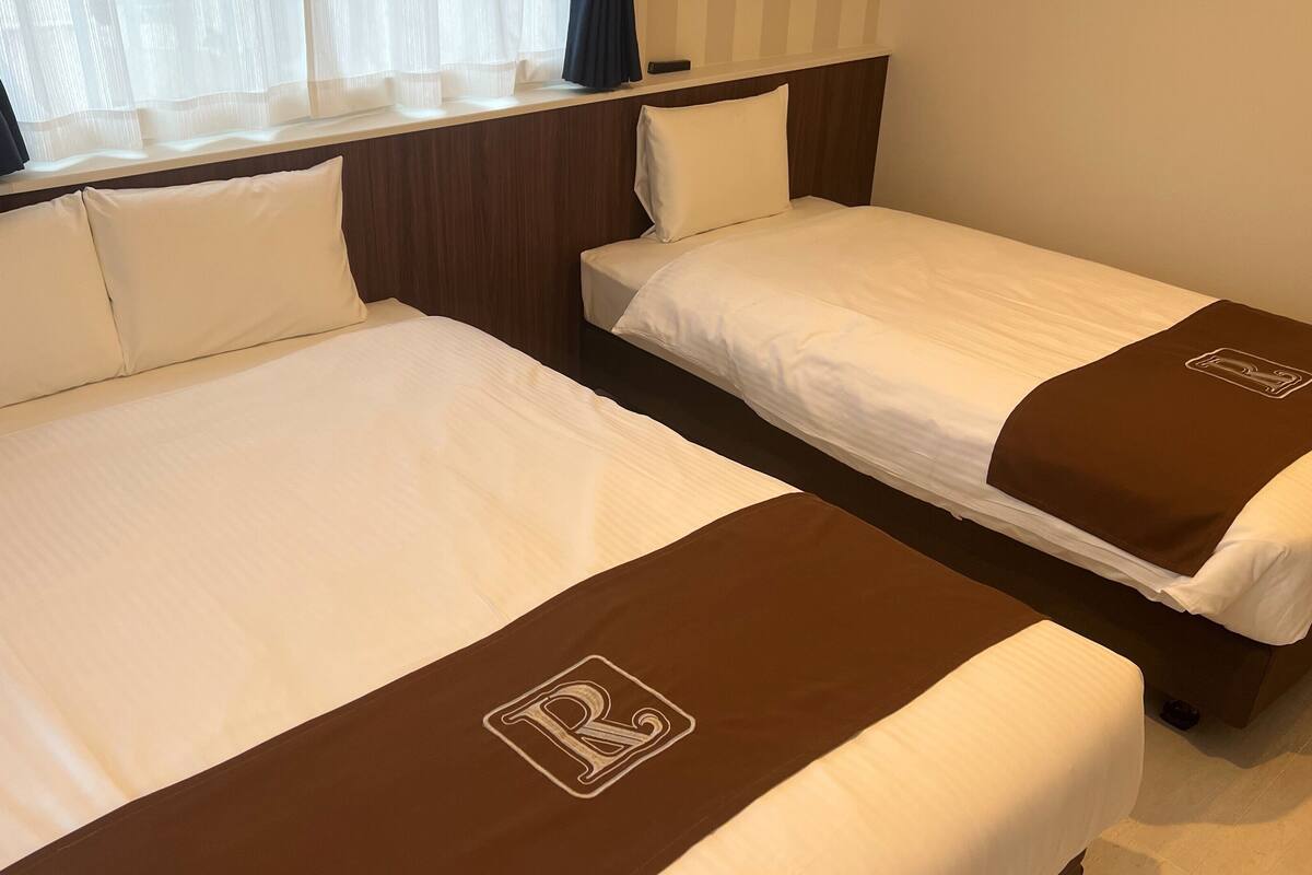 Two single beds with white linens and brown headboards, each with a logo on the footboard.