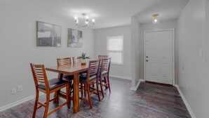 A dining area with a wooden table and chairs, a chandelier, and two wall-mounted light fixtures. - Stylish townhome, sleeps 8, pet friendly.  (Augusta)