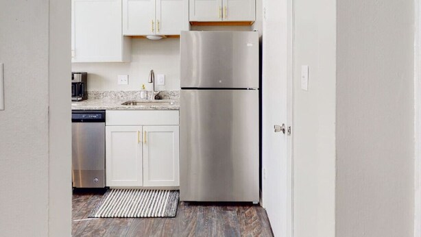 A modern kitchen with white cabinets, stainless steel appliances, and a striped rug. - Stylish townhome, sleeps 8, pet friendly.  (Augusta)