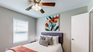 A bedroom with a bed, a ceiling fan, a window with blinds, and a door. - Stylish townhome, sleeps 8, pet friendly.  (Augusta)