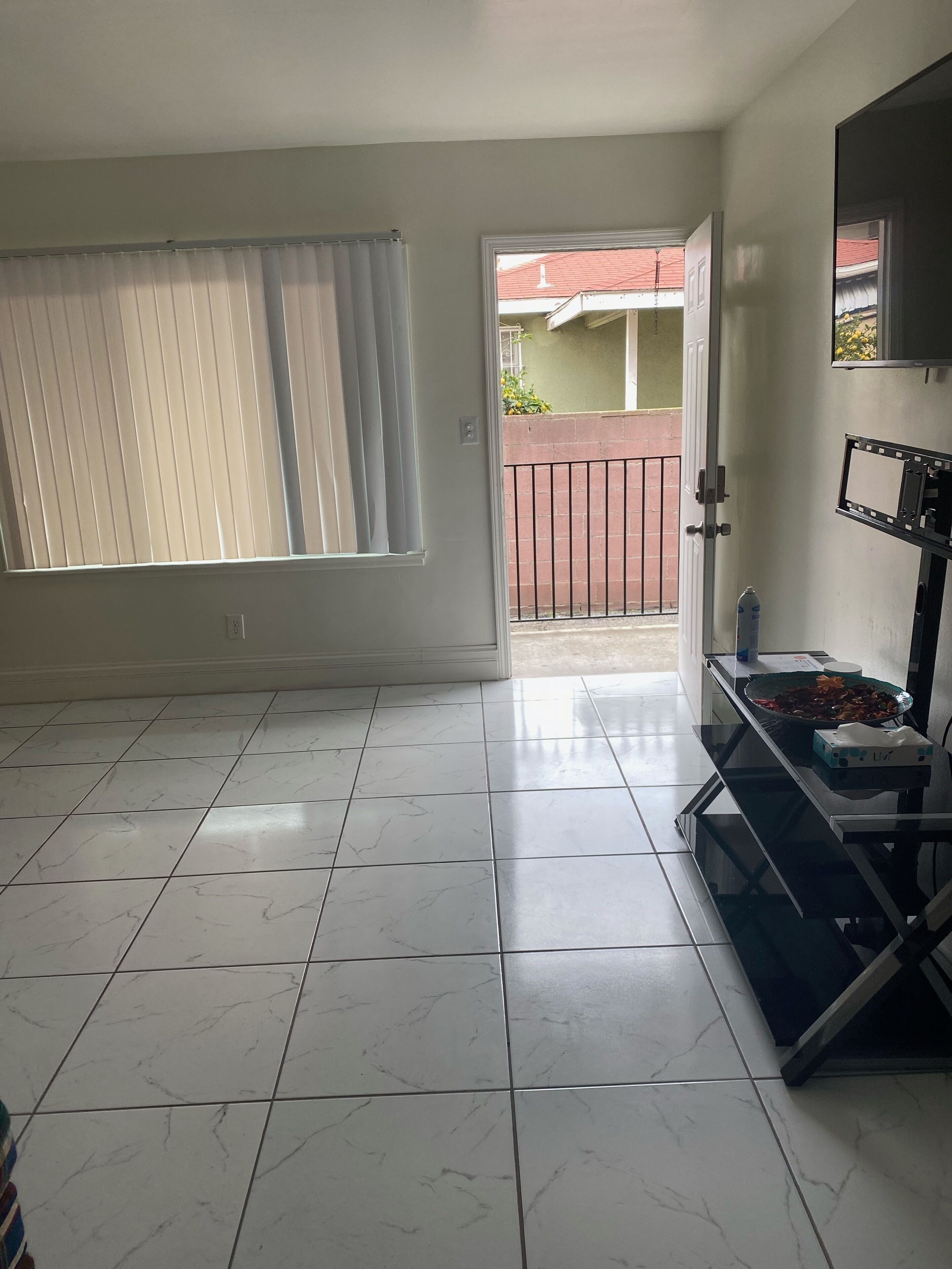 Een ruime kamer met een groot raam, een balkon en een eethoek met een tafel en stoelen.