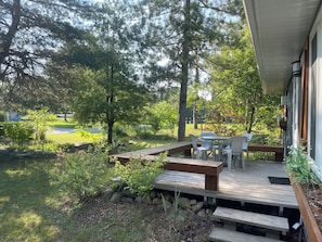 Relax on the elevated deck, surrounded by lush greenery, with a table and chairs for outdoor dining or unwinding.
