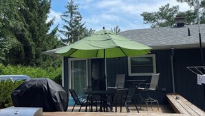 Una terrazza con mobili da esterno, un barbecue e una zona coperta con tavolo e sedie.