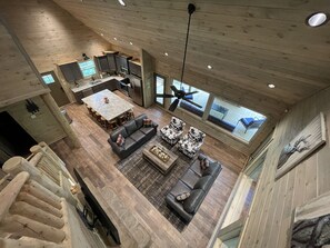 Un vaste espace de vie aménagé dans un style industriel, avec une table à manger, des canapés et une cuisine en arrière-plan.