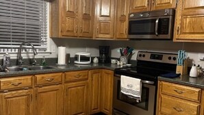 Una cocina con gabinetes de madera, un microondas, un horno y un lavamanos.
