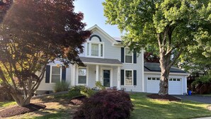 A two-story house with a front porch, a garage, and a well-maintained lawn.