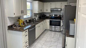 A modern kitchen with white cabinets, stainless steel appliances, and a granite countertop.