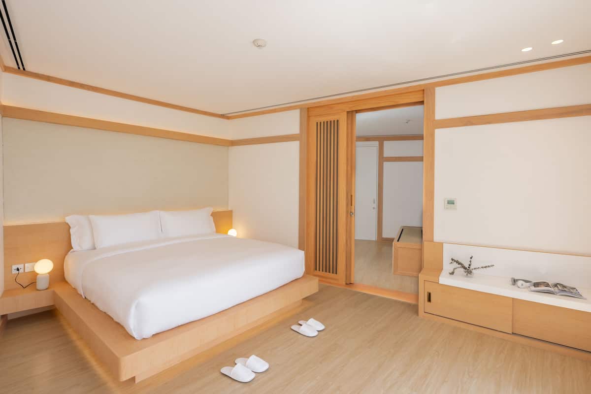 A modern hotel room with a large bed, bedside table, and a mirror.