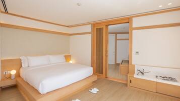 A modern hotel room with a large bed, bedside table, and a mirror.