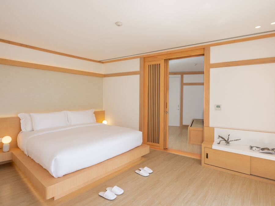 A modern hotel room with a large bed, bedside table, and a mirror.
