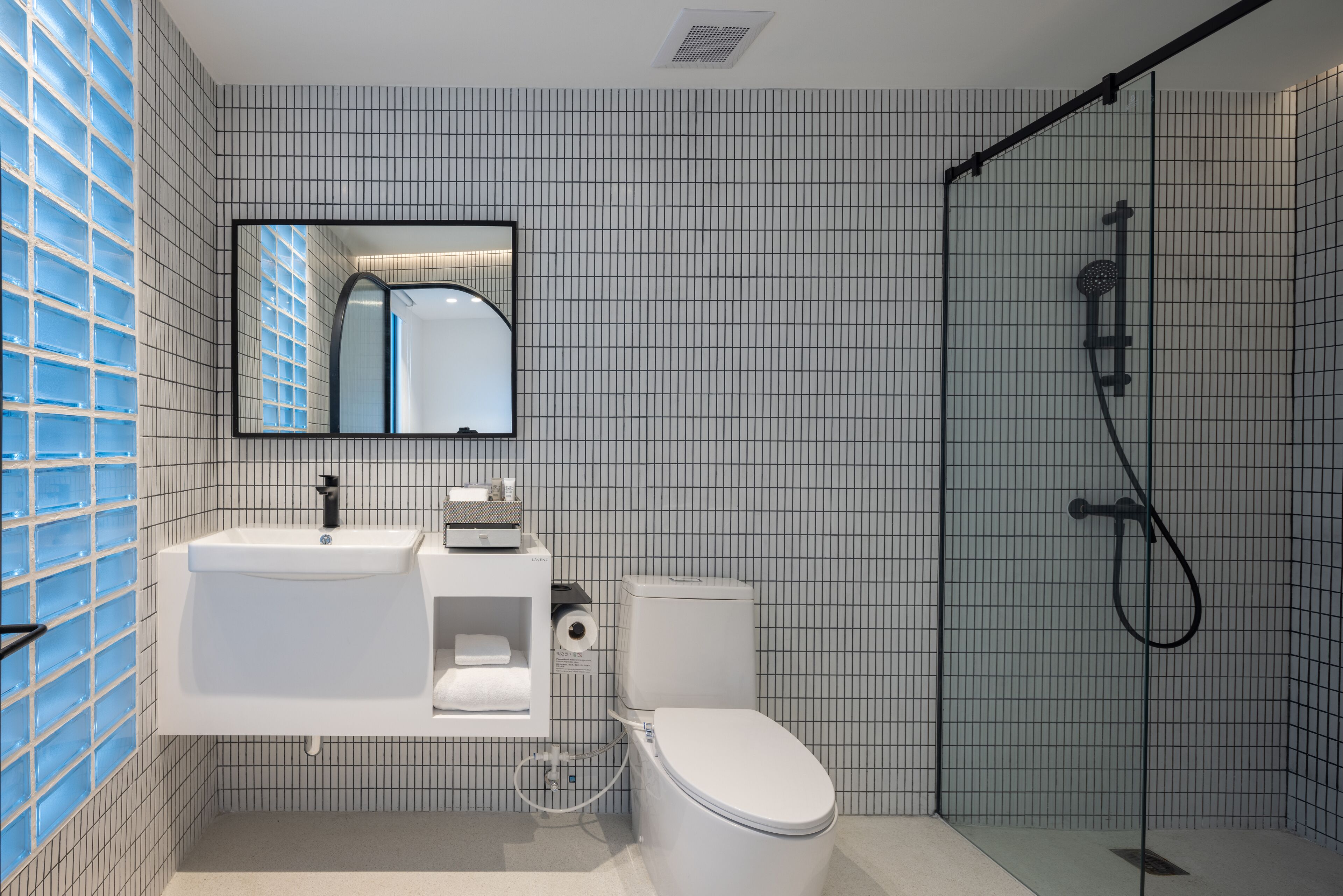 A modern bathroom with a white sink, toilet, and shower.