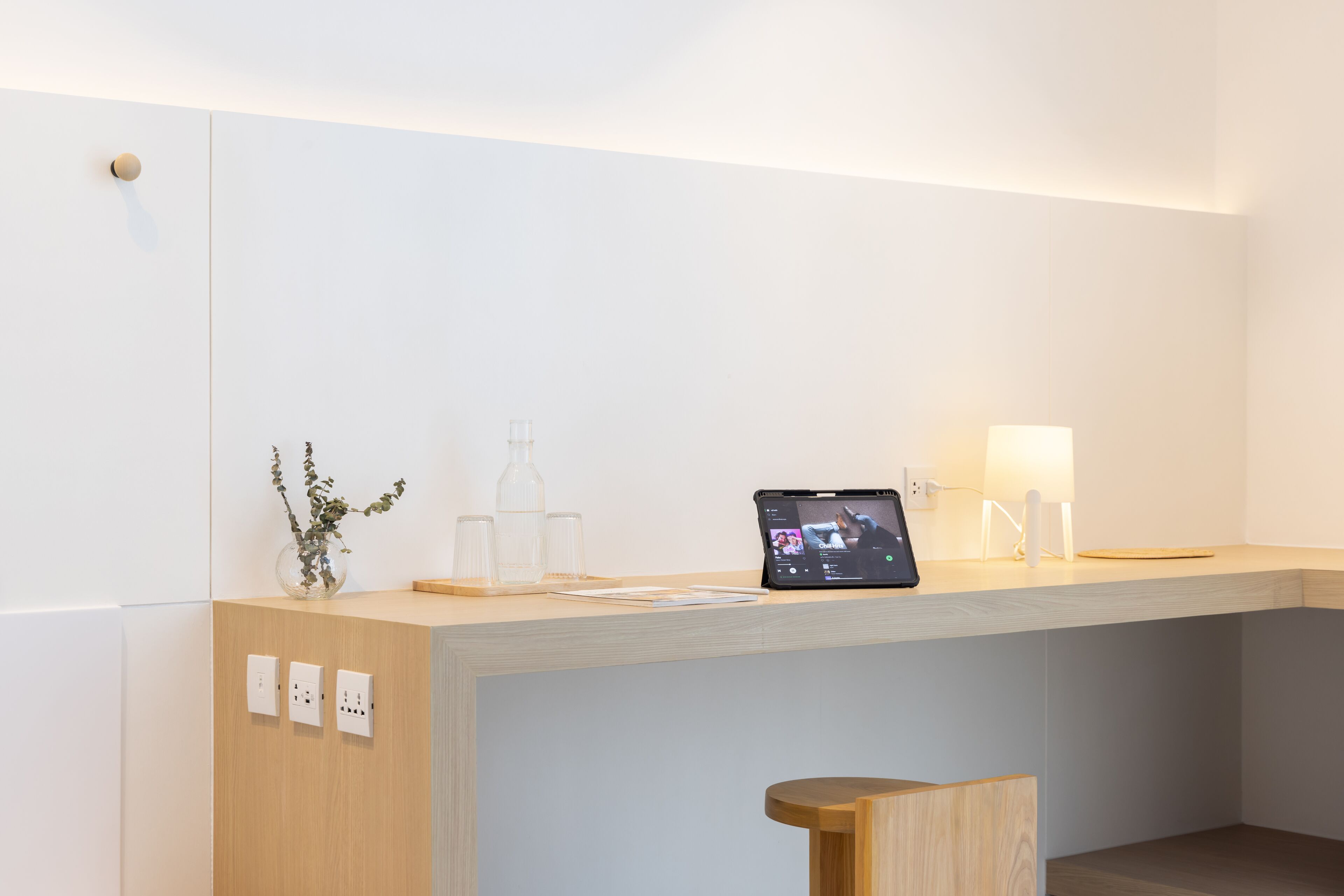 A modern reception desk with a laptop, a vase with plants, and a lamp.