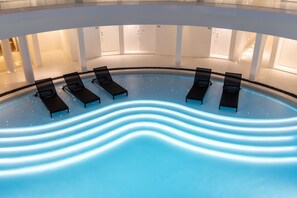 A modern indoor swimming pool with six lounge chairs and a wavy pool edge. - G Nimman Chiang Mai (Chiang Mai)