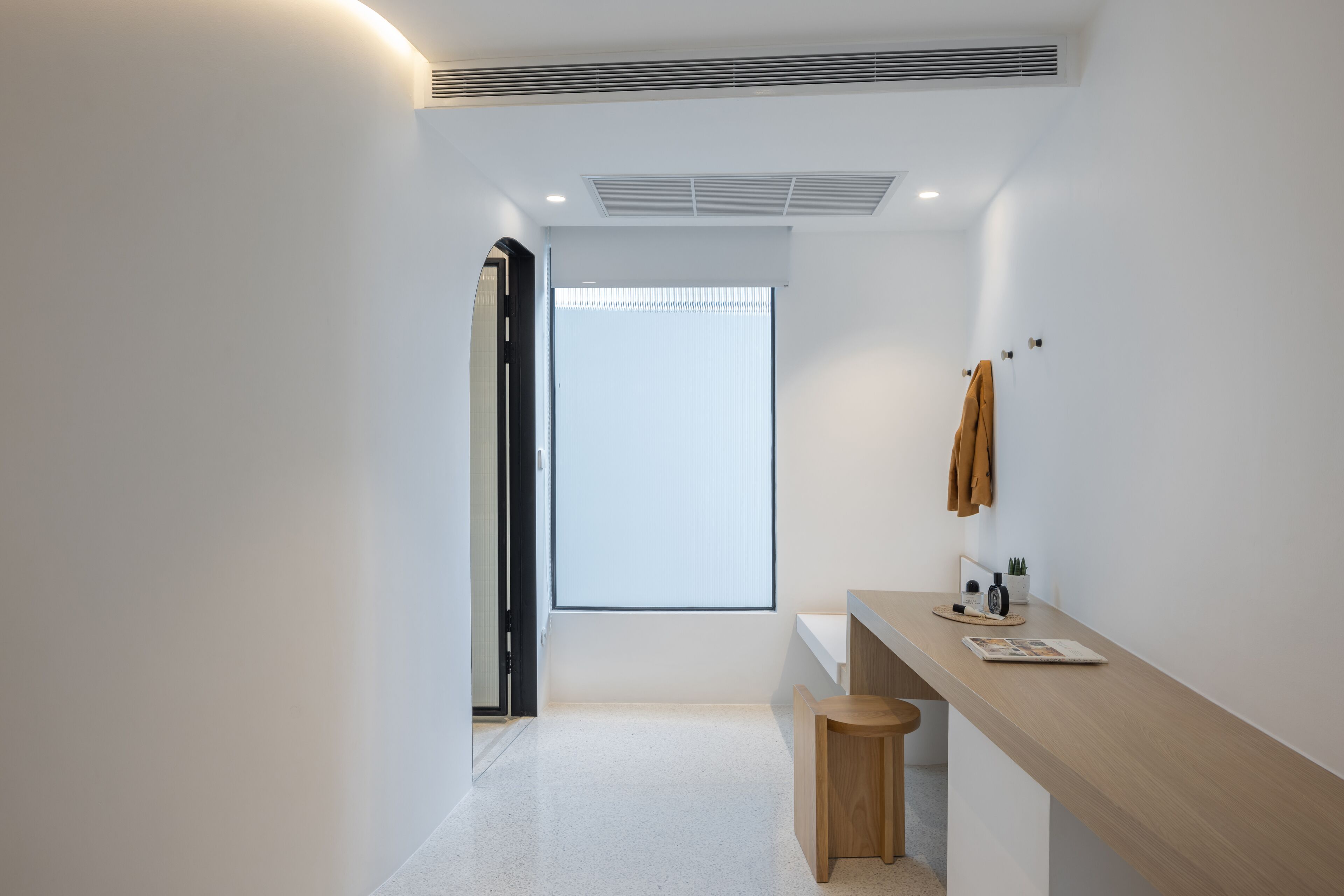 A modern bathroom with a wooden vanity, a towel rack, and a window with blinds.