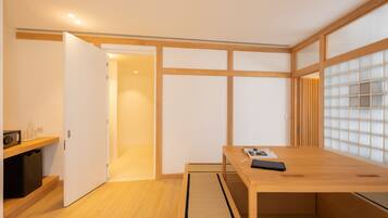 Una habitación minimalista con un escritorio de madera, un estante pequeño y una puerta corredera que da a otra habitación.