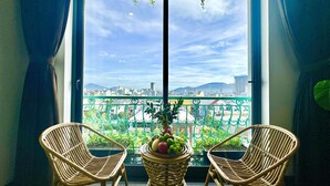 A balcony with wicker chairs, a potted plant, and a view of a cityscape. - Century Hotel (Da Nang)