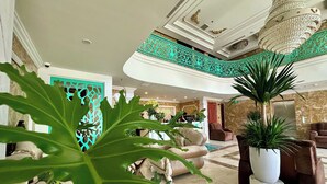 A hotel lobby with a reception desk, seating area, and a staircase with decorative railings. - Century Hotel (Da Nang)