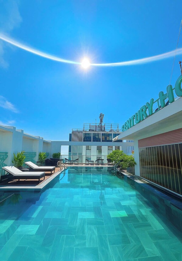 A rooftop pool with lounge chairs and a modern building in the background.