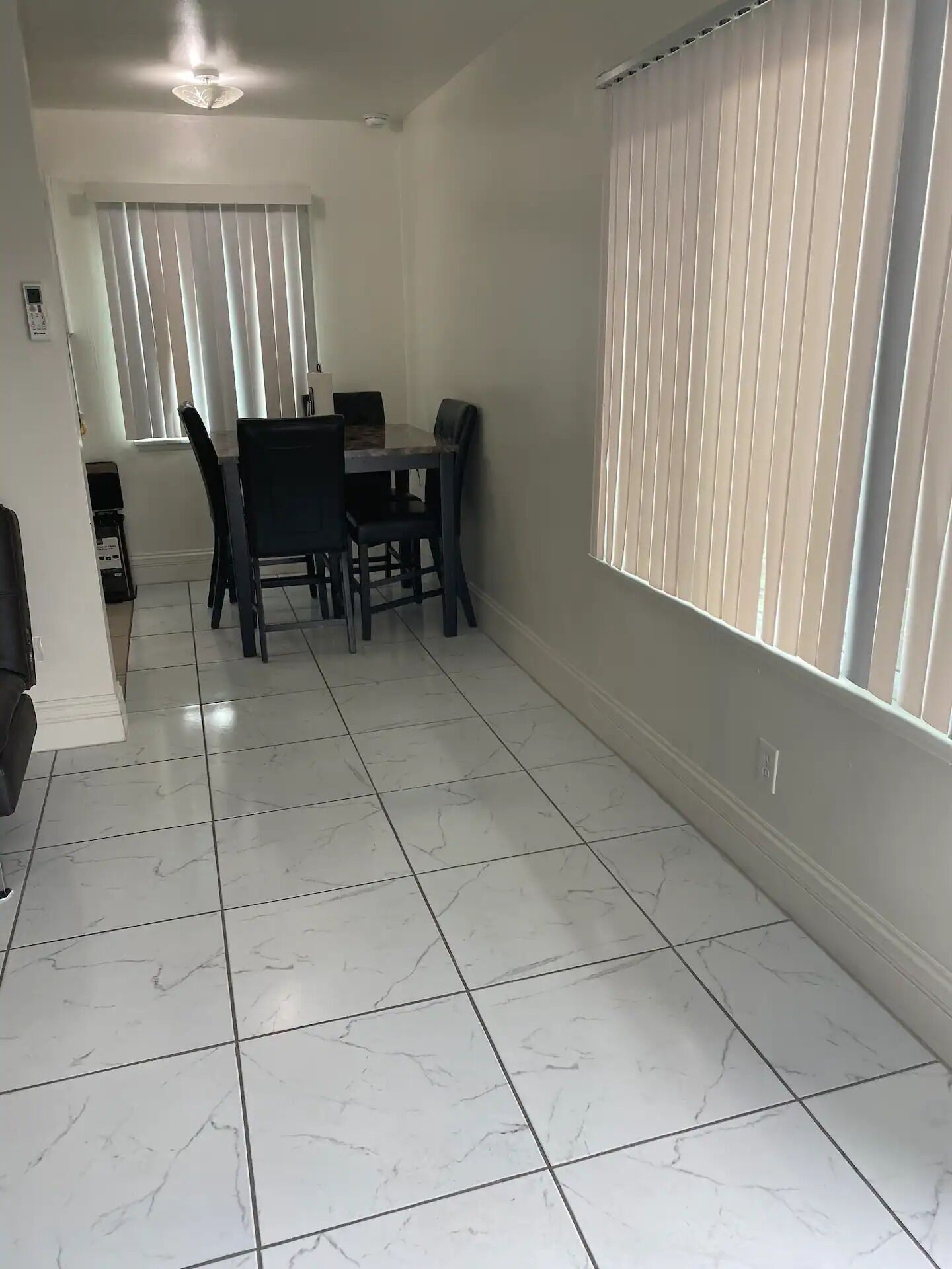 A dining area with a table and chairs, a ceiling fan, and a window with blinds.