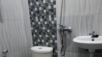 A bathroom with a toilet, a shower, and a sink.