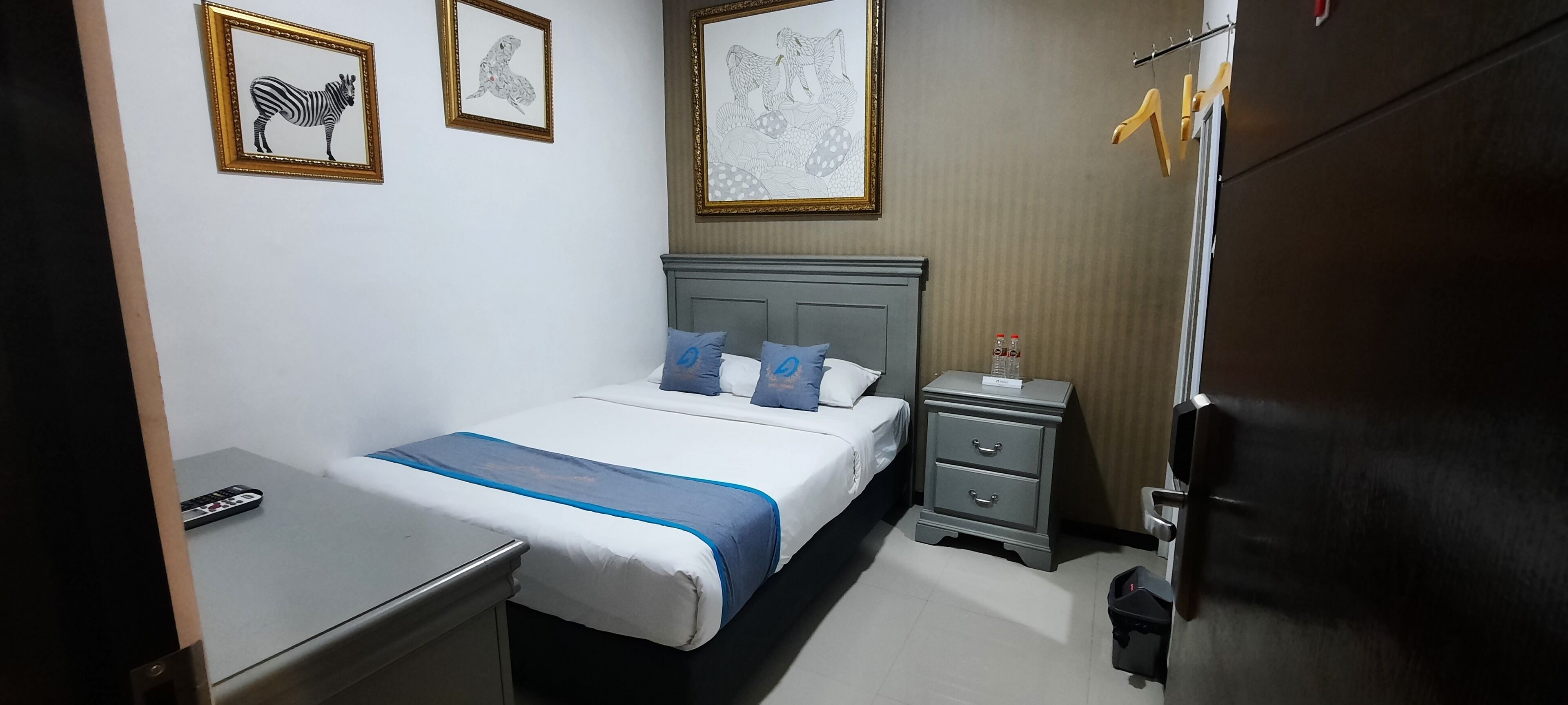 Habitación de hotel ordenada con cama, mesitas de noche, escritorio y armario.