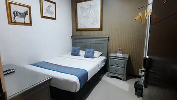 Habitación de hotel ordenada con cama, mesitas de noche, escritorio y armario.