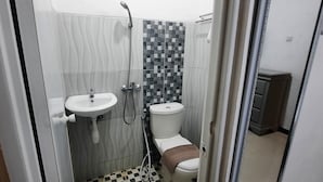 Un bany petit amb un lavabo blanc, un vàter i una zona de dutxa.