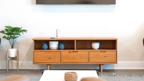 Ein modernes Wohnzimmer mit einem Holzschrank, einem weißen Couchtisch und einer Topfpflanze.