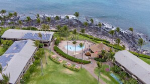 Luchtbeeld van een resort met een zwembad, zonnepanelen en een strand.