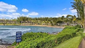 Blick auf die Küste mit Warnschild, Strand und Hotelgebäuden.