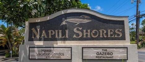Un letrero de Napili Shores con la indicación 'Hawaii Vacation Condos' y 'The Gazebo Restaurant'.