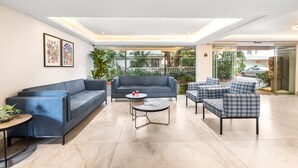 A modern lobby with a blue sofa, a round coffee table, and a checkered armchair. - Ocean Palms Goa (Calangute)
