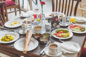A breakfast table with various dishes, including eggs, toast, and fruit, along with cups of coffee and tea. - Ocean Palms Goa (Calangute)