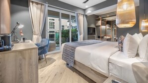 A modern hotel room with a large bed, a desk, a chair, and a balcony with curtains. - Ocean Palms Goa (Calangute)