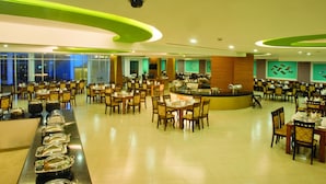 A spacious dining area with multiple tables and chairs, a buffet line with food containers, and a counter with a coffee machine. - Sea Pearl Beach Resort & Spa Cox's Bazar (Cox's Bazar)