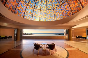 Un hall d’entrée spacieux, doté d’un grand plafond en vitrail aux couleurs vives et offrant une vue sur l’océan.