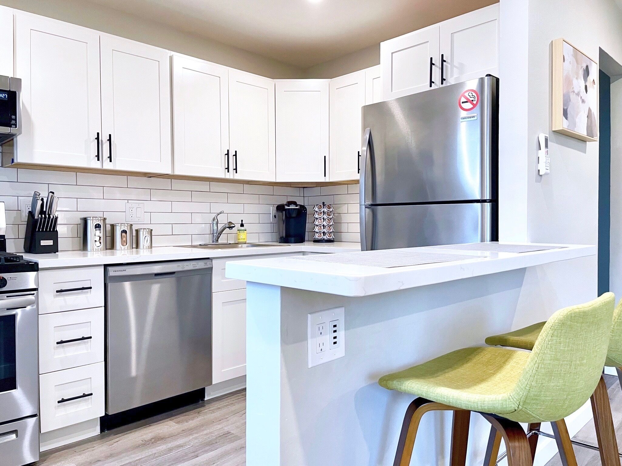 A modern kitchen with white cabinets, stainless steel appliances, a built-in island, and a coffee maker.