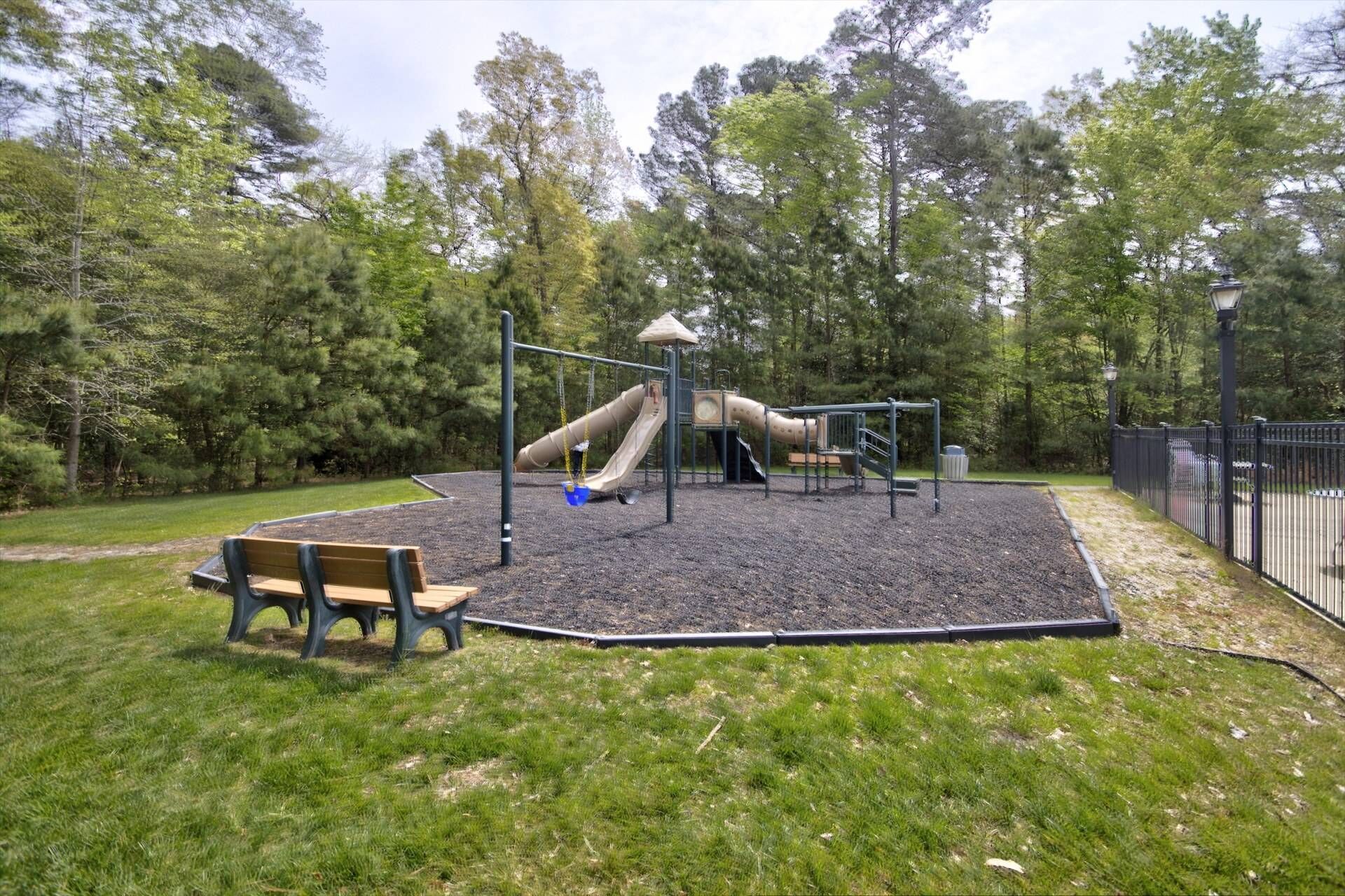 A playground with a slide, swings, and a bench.