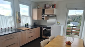 Une cuisine moderne avec des meubles en bois, un four encastré et un coin repas comprenant une table et des chaises.