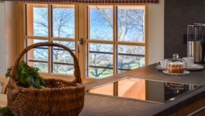 A kitchen with a window, a basket, a coffee maker, and a tea set.