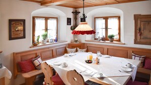 A dining area with a large table set for four, wooden benches, and a hanging light fixture.