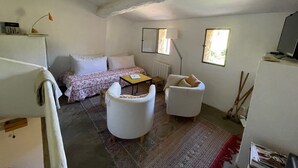 Une petite pièce agréable et chaleureuse, avec un lit, deux chaises blanches, une petite table et un radiateur. Deux fenêtres laissent entrer la lumière naturelle.